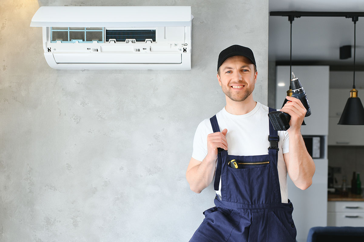 Smiling Young Male Electrician Repair Conditioner In Client Home. Man Mechanic Or Repairman Fix Filters In Air Condition Device At Customer House